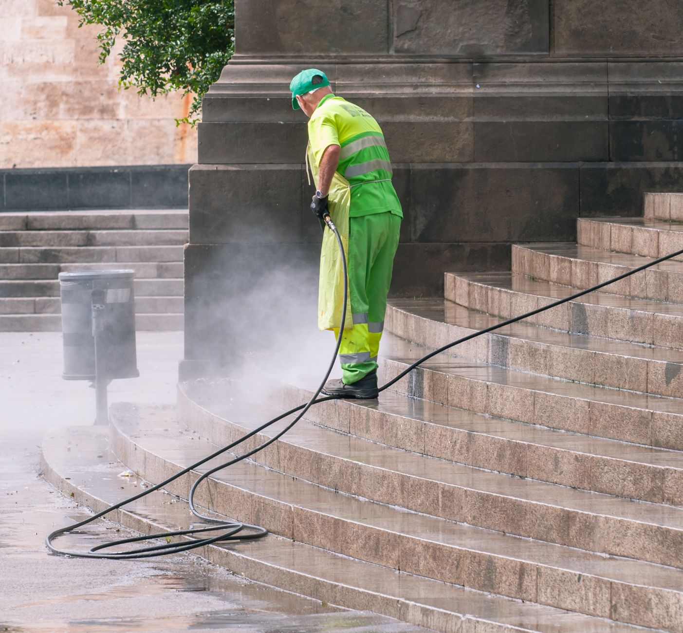 A worker pressure washing stone steps outdoors