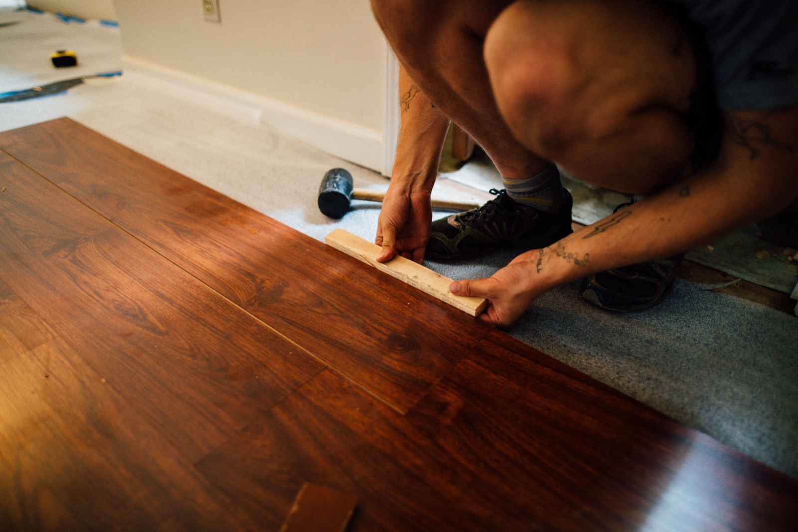 An installer laying dark wood plank flooring