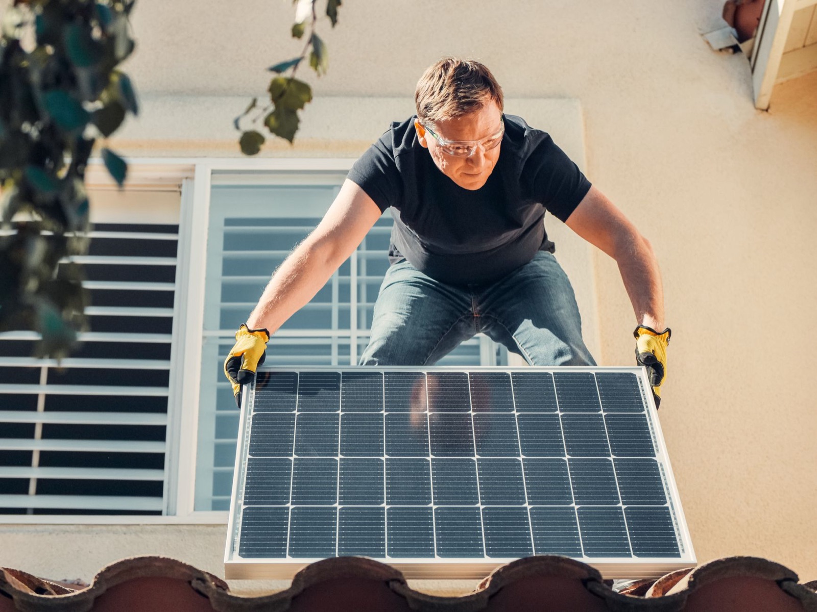 An installer lifting a solar panel into place on a rooftop