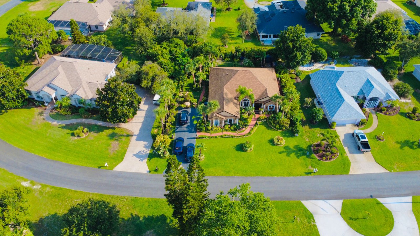 Aerial view of single-family Florida homes with tile roofs, screened pool cages and green lawns